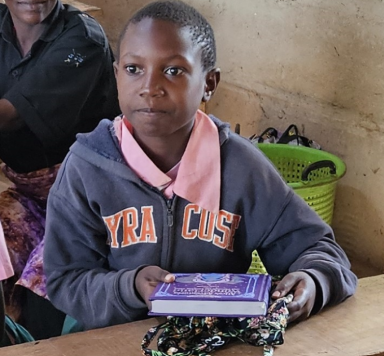Ein Junge hält ein Buch in den Händen und schaut aufmerksam. Er trägt einen grauen Hoodie.