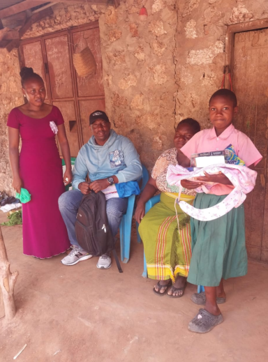 Eine Gruppe von vier Personen steht und sitzt in einer einfachen Hütte.