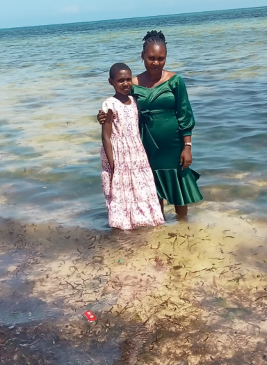 Zwei Frauen stehen im Wasser, eine trägt ein grünes Kleid, die andere ein weißes Kleid.